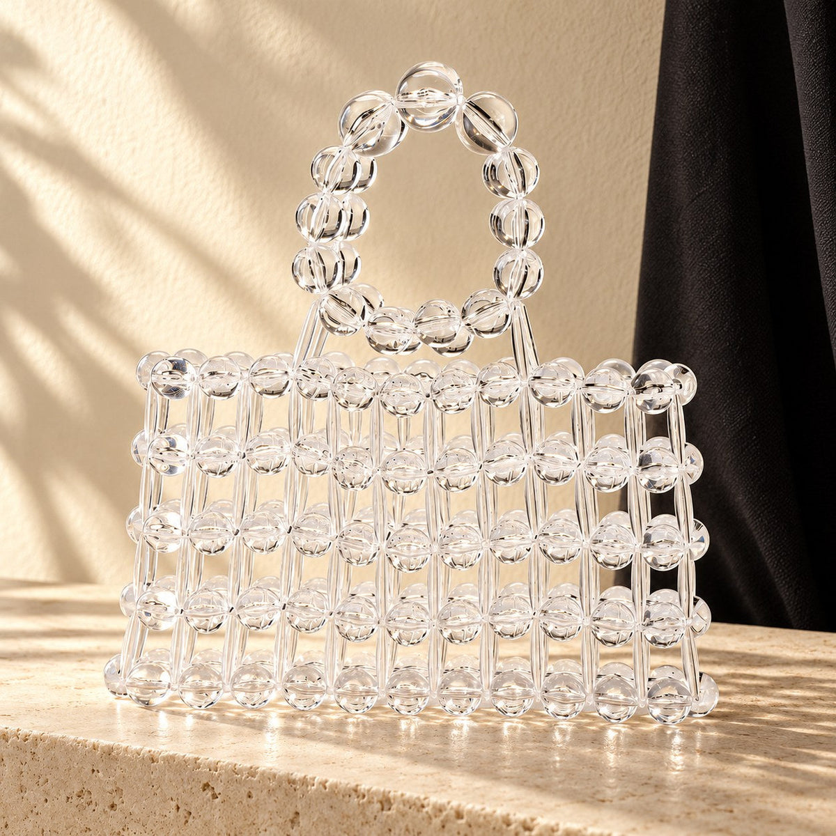 Clear acrylic beaded handbag on a limestone console.